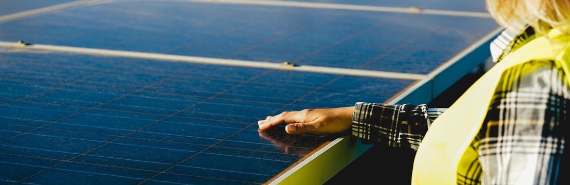 Kvinnlig elinstallatör på tak med solceller.