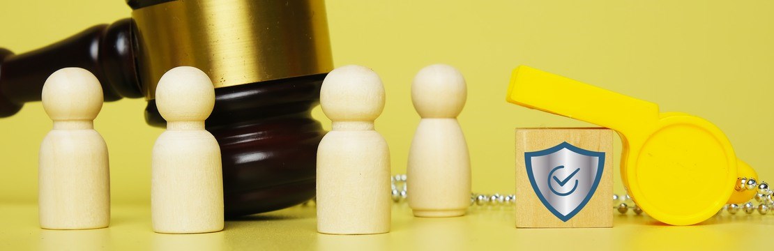 Domarklubba och visselpipa med små trägubbar i förgrunden och en träkloss med en avtecknad skyddssköld.