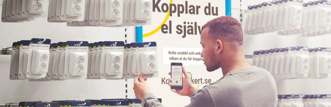 Manlig kund väljer elprodukter i butiksmiljö.