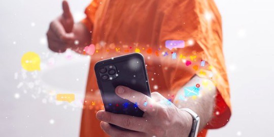 Elev i orange skjorta med en telefon.