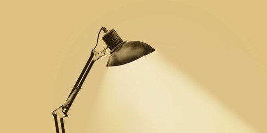 Illuminated vintage rusty desk lamp with flexible arms on a sepia background