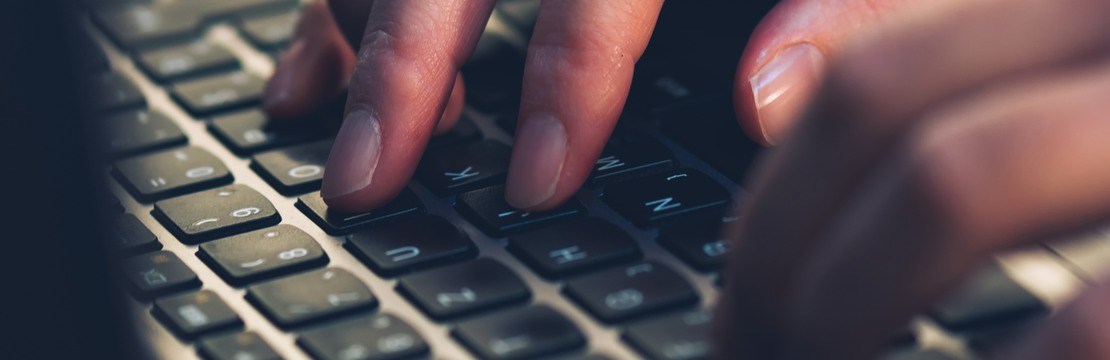 Närbild på händer vid ett tangentbord.