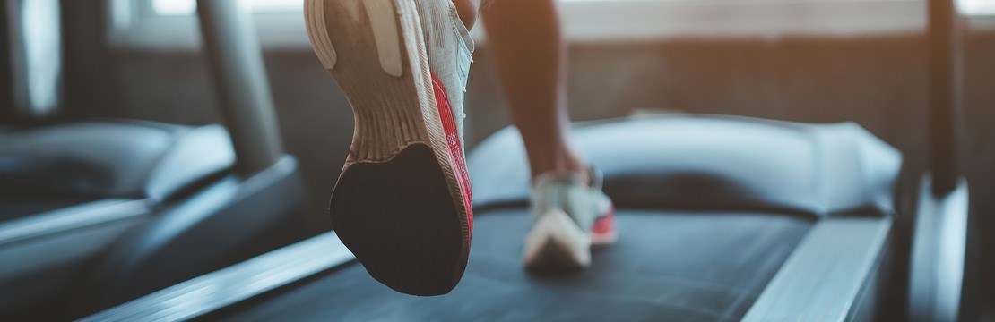 Close up of feet, sportman runner running on treadmill in fitness club. Cardio workout. Healthy lifestyle, guy training in gym. Sport running concept