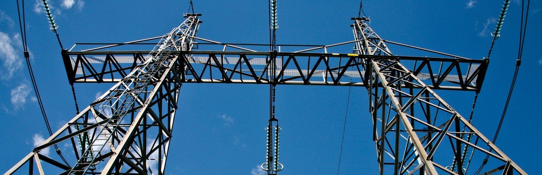 Kraftledningsstolpar mot blå himmel som bakgrund.