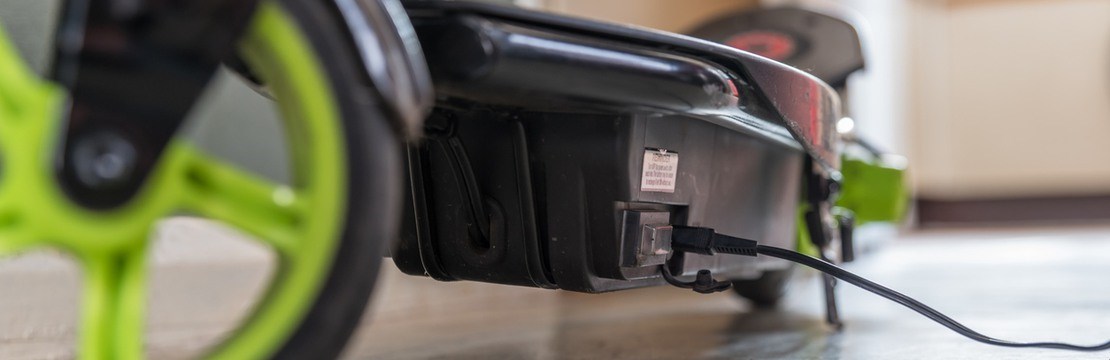 Elsparkcykel med gröna hjul på laddning.