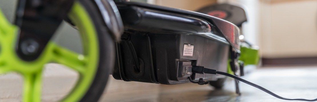 Elsparkcykel med gröna hjul på laddning.