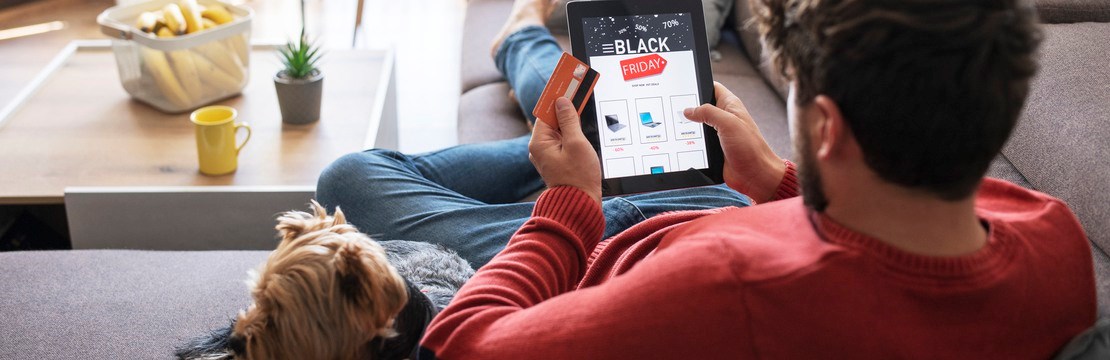 Kille ligger i soffa med en ipad och kollar på Black Friday-reklam.