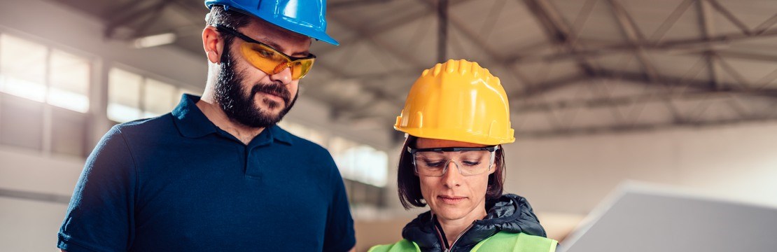 En man och en kvinna i skyddshjälm antecknar i ett block.