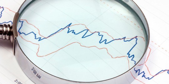 Närbild på förstoringsglas som ligger på papper med statistik.