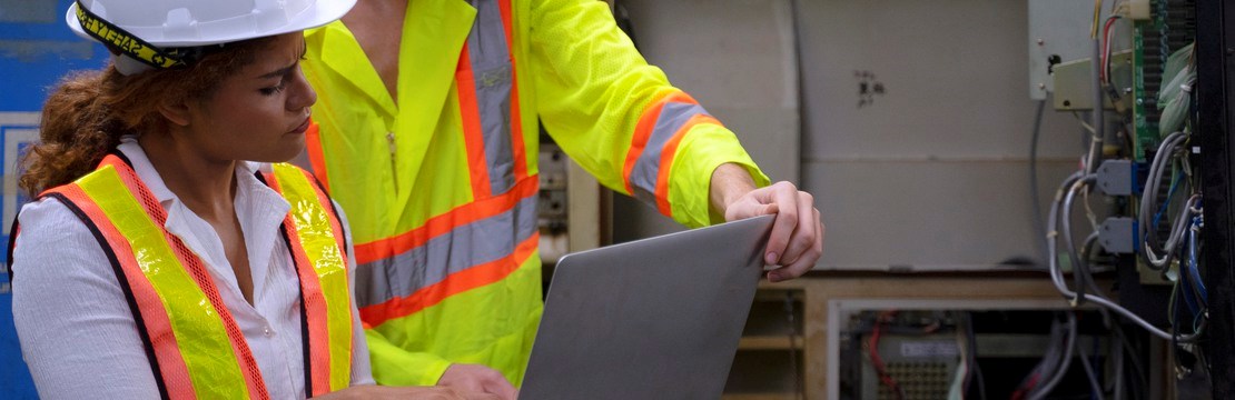 Kvinna och en man med dator i industrimiljö.