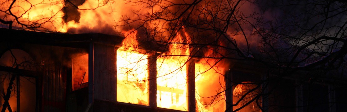 Övertänt hus med stora lågor.