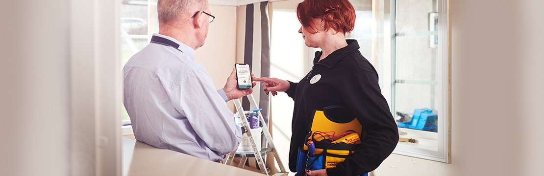 Privatperson renoverar hemma och pratar med en elinstallatör samtidigt som de tittar på en mobilskärm.