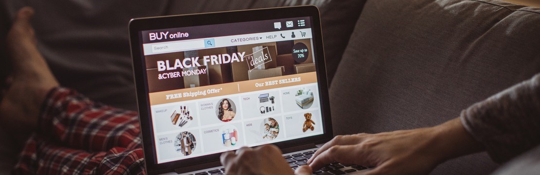 Kille i soffa kollar på datorn inför black friday.