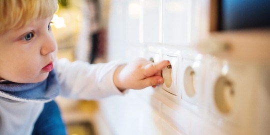 Litet barn petar med fingret i ett vägguttag.