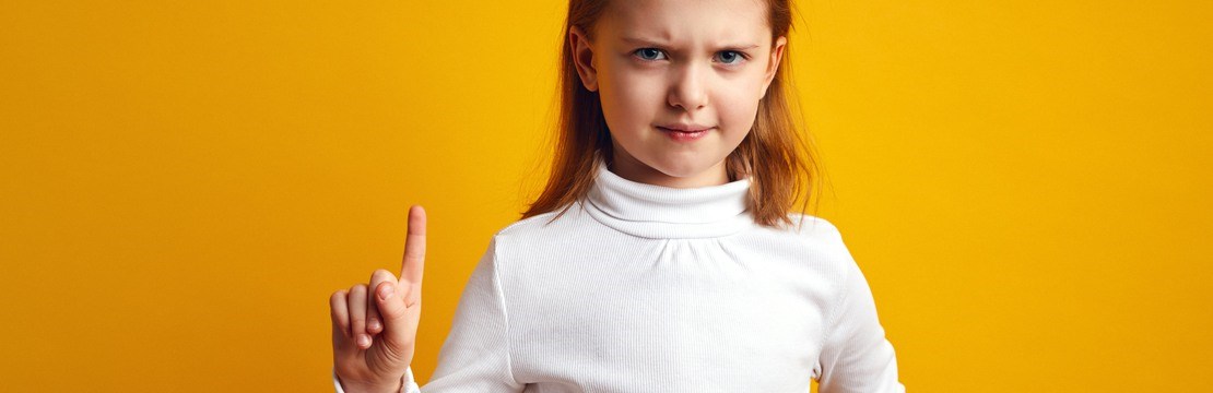 Flicka med bestämd uppsyn håller upp sitt pekfinger.