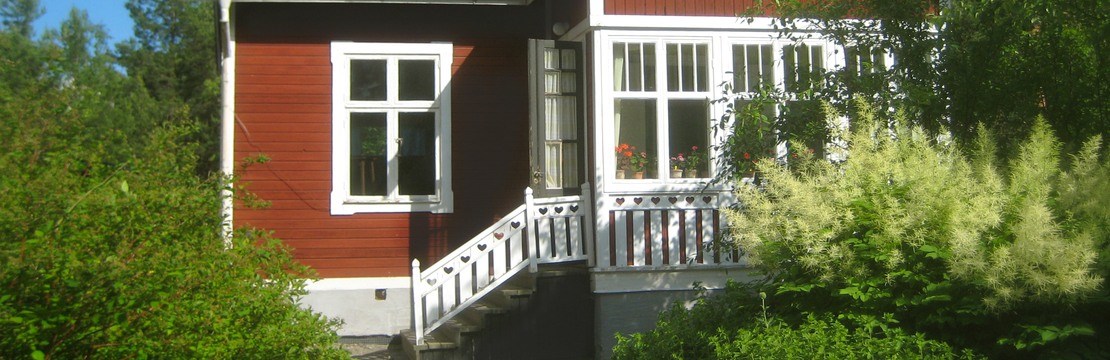 Litet rött hus med vitmålad trappa.