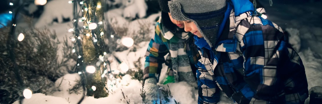 barn leker i snö, ljusslinga bredvid dem
