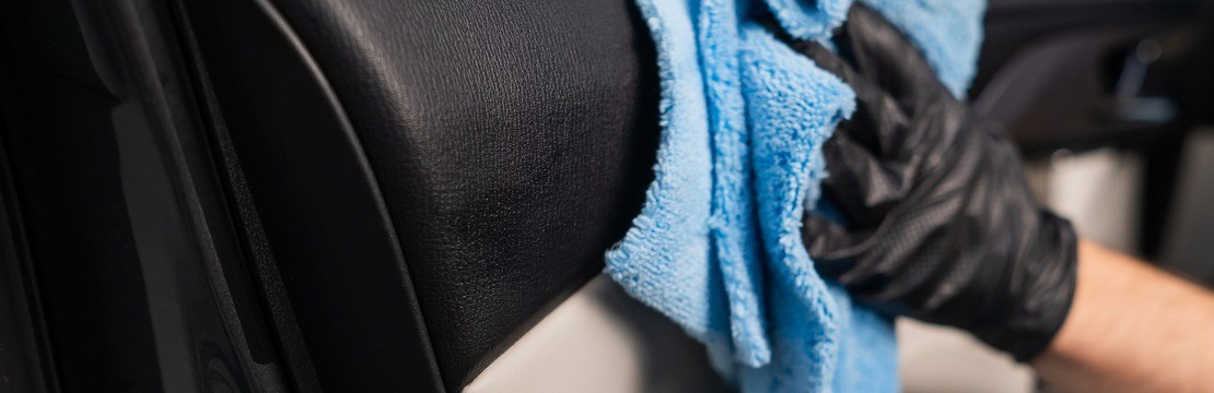 En person torkar insida av bildörr med trasa