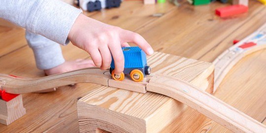 Barnhand håller i ett leksakståg. Child playing with train