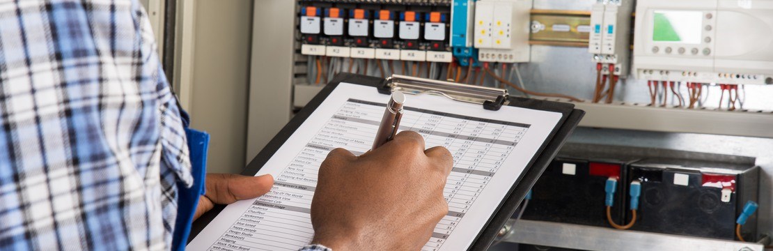 En elinstallatör framför en elcentral med checklista.