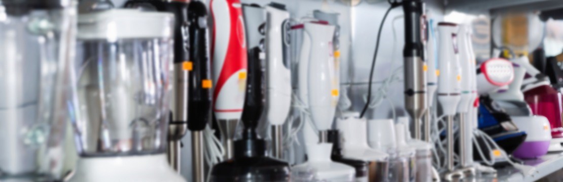 Young glad cheerful  female is choosing new blender for his kitchen in appliances store