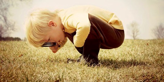 Ett barn granskar gräsmatta med förstoringsglas.