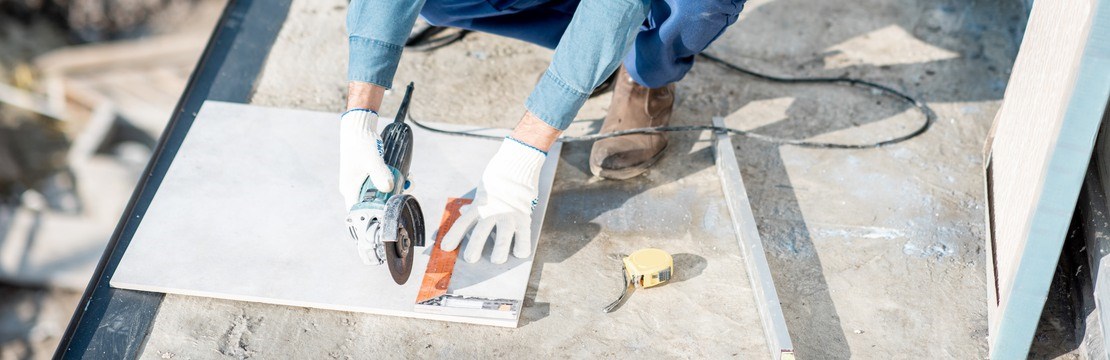 Workman in uniform mounting ceramic tiles on the balcony at the construction site