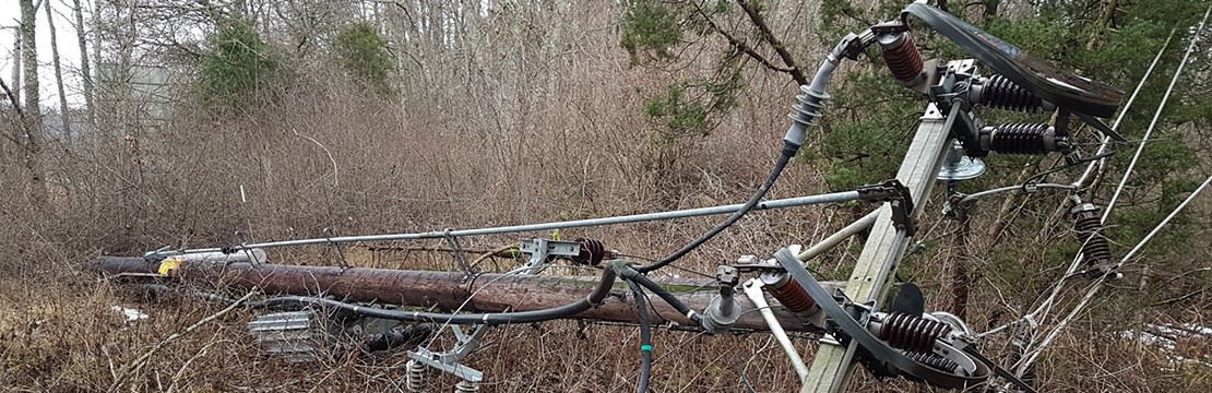 Nedblåst kraftledningsstolpe som ligger på marken