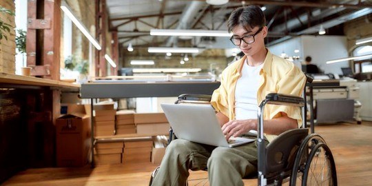 Ung kille i rullstol med laptop i knät.