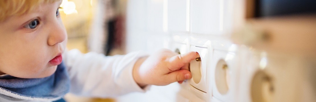 Litet barn sticker fingret i ett vägguttag