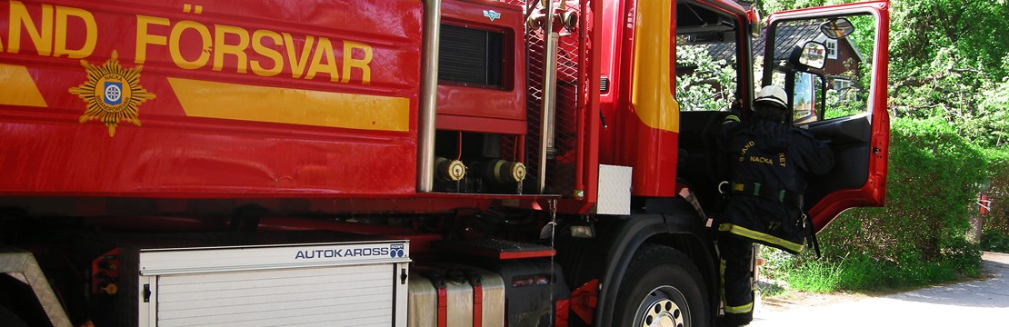 En människa i brandförsvarskläder kliver in i en brandbil.