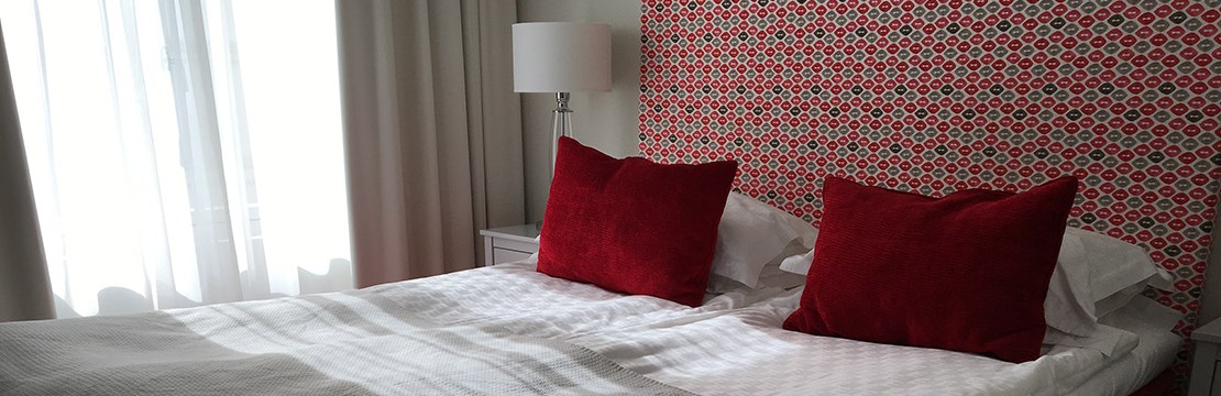 Bild på hotellrum med röda kuddar på en säng