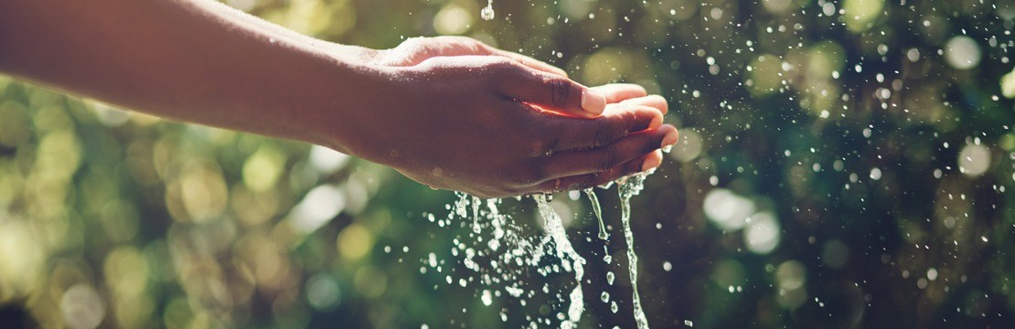 Händer fångar upp vatten utomhus