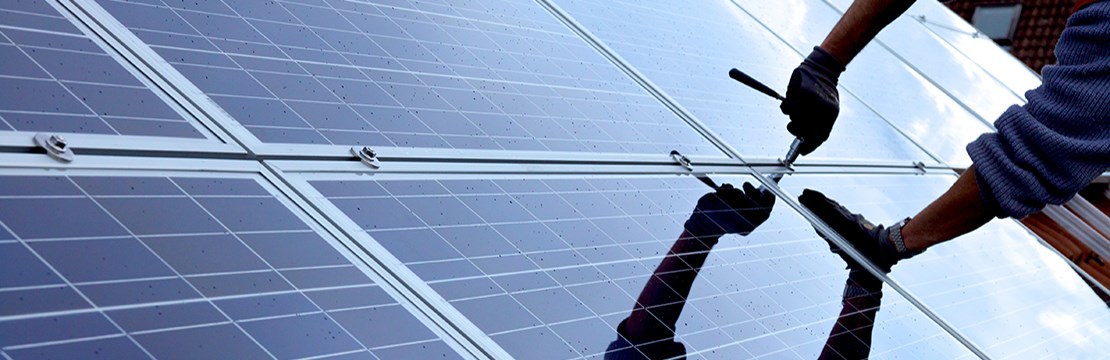 Hand skruvar fast solceller på tak