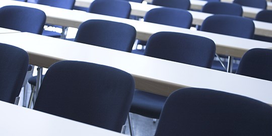 Rader av tomma stolar i föreläsningssal
