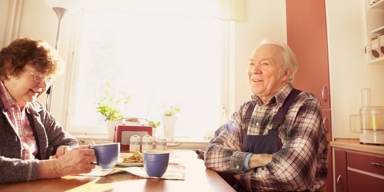 Two elderly people having a conversation over coffee.