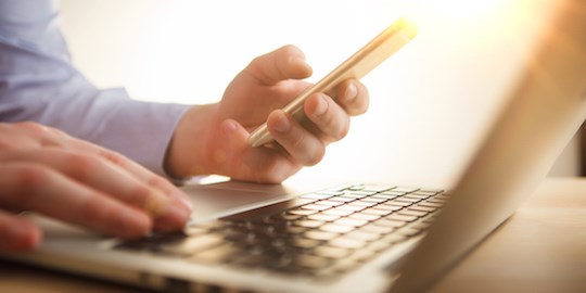 Person using a smartphone and laptop.