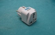 Vit reseadapter i plast på turkos yta