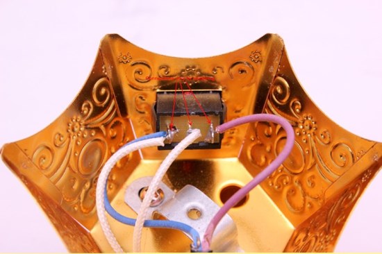 Insida av toppen på guldfärgat rökelsekar. visar en rosa kabel, en blå kabel samt två vita.
