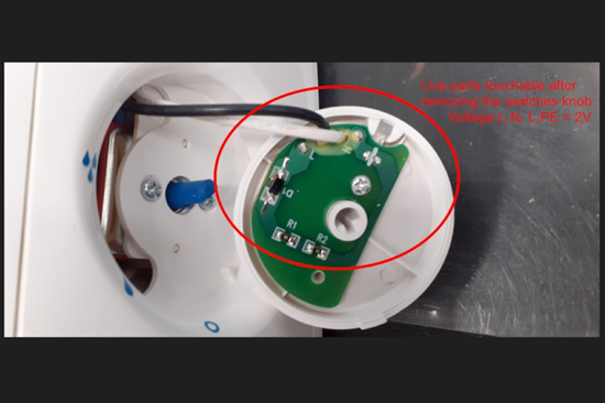 Insidan av vit knapp som går att ta bort där en grön bricka är synlig  och spänningsfarliga delar kan vidröras