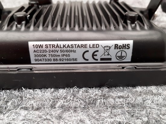 Silvrig klisterlapp med texten 10W strålkastare LED, AC220-240V 50/60Hz, 3000K 750lm IP65, 9047330 88-92160/SE, CE-märke. 