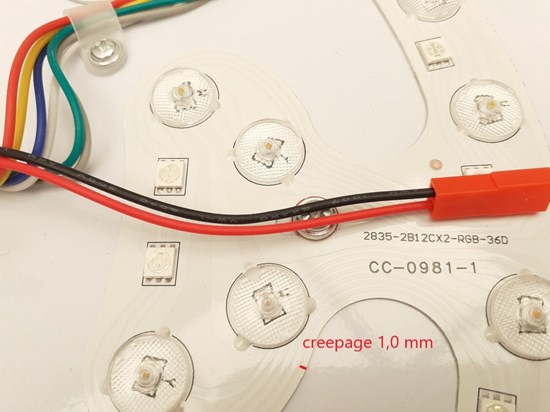 Röd och svart kabel som löper över lampan. Text som visar krypavstånd på 1,0 mm