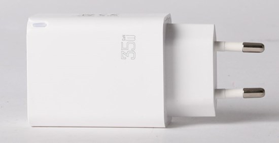 Vit USB-laddare mot grå bakgrund.